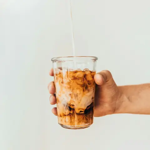 Cold brew coffee in a glass, held in hand